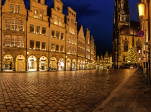 Beleuchtete Altstadt mit Kopfsteinpflaster und gotischer Kirche bei Nacht.