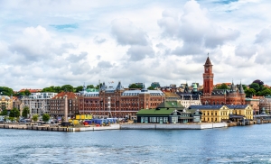 Küstenstadt mit historischen Gebäuden und Wasserturm bei bewölktem Himmel.