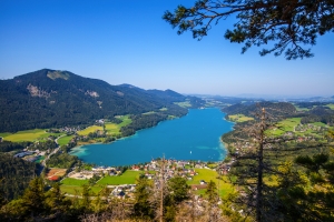 Blick auf einen klaren blauen See inmitten grüner Berge und Dörfer.