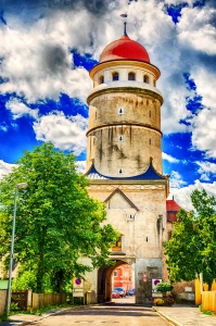 Historischer Turm mit rotem Dach unter blauem Himmel mit Wolken.
