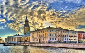 Historisches Gebäude an einem Fluss bei Sonnenuntergang mit dramatischem Himmel.