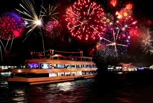 Ein beleuchtetes Schiff mit Feuerwerk am Nachthimmel.