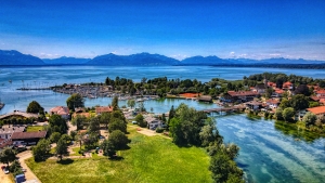 Luftaufnahme einer malerischen Landschaft mit See, Insel und Bergen im Hintergrund.