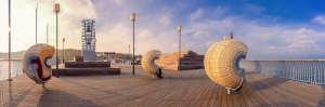 Seebrücke Koserow auf der Insel Usedom in Mecklenburg-Vorpommern, Deutschland, mit Blick auf die Ostsee und einer offenen, hölzernen Plattform mit mehreren Sitzmöglichkeiten.