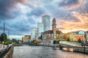 Skyline von Malmö mit modernen und historischen Gebäuden am Flussufer bei Sonnenuntergang.