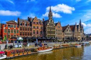 Historische Gebäude am Flussufer mit Booten und blauem Himmel.