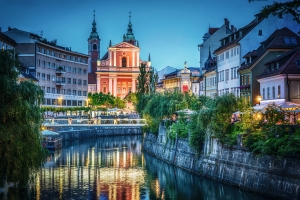 Stadtansicht bei Nacht mit Kirche und Fluss in Ljubljana, Slowenien.
