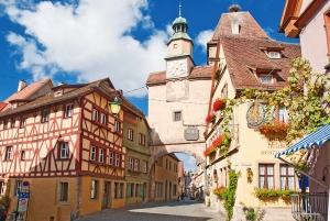 Historisches Stadttor und Fachwerkhäuser bei sonnigem Wetter.