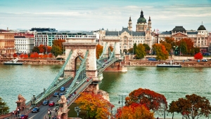 Historische Kettenbrücke über Fluss mit Stadt im Hintergrund.