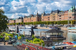 Uferpromenade mit Fahrrädern, Geschäften und historischen Gebäuden am Wasser.