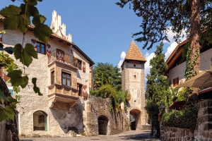 Mittelalterlicher Turm und historische Gebäude an sonniger Gasse.