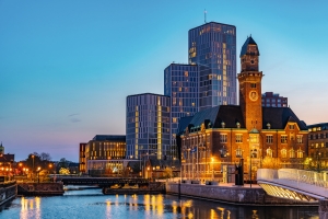 Stadtsilhouette mit modernen und historischen Gebäuden bei Sonnenuntergang entlang eines Kanals