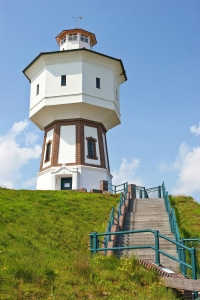 Wasserturm auf grünem Hügel mit blauen Himmel und Treppe im Vordergrund