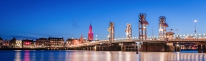 Beleuchtete Brücke und Gebäude in einer Stadt bei Nacht.