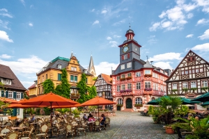 Historischer Marktplatz mit Fachwerkhäusern und rotem Sitzbereich im Freien.