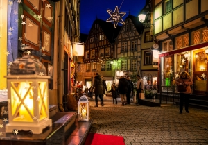 Beleuchtete Altstadtgasse mit Fachwerkhäusern und Laternen in der Abenddämmerung.