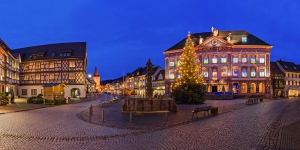 Beleuchteter Marktplatz mit Weihnachtsbaum und Fachwerkhäusern bei Dämmerung.