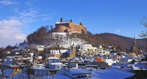 Verschneite Stadt Kulmbach mit Burg auf einem Hügel im Hintergrund.