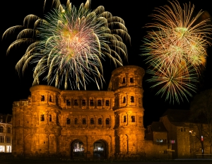 Alte römische Stadttor-Ruine bei Nacht mit Feuerwerk im Hintergrund.