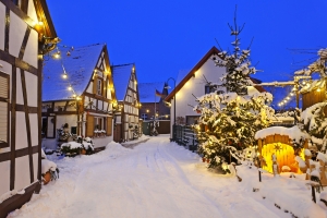 Verschneite Dorfstraße mit Fachwerkhäusern und weihnachtlicher Beleuchtung