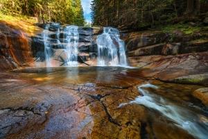 Wasserfall inmitten eines bewaldeten Gebiets mit klaren Wasserströmungen.