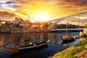 Boote im Fluss Douro bei Sonnenuntergang, Brücke und Stadtansicht im Hintergrund.