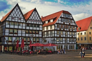 Fachwerkhäuser an einem Marktplatz mit Passanten und Cafés.