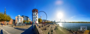 Panoramaaufnahme der Rheinuferpromenade in Düsseldorf bei sonnigem Wetter.