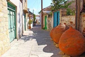 Schmale Gasse mit alten Gebäuden und großen Tonkrügen im Freien.