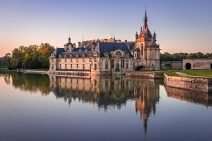 Schloss mit spiegelndem Wasser im Sonnenuntergang.
