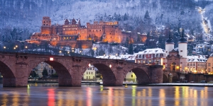 Heidelberger Schloss bei Nacht mit beleuchteter Alter Brücke im Winter.