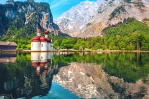 Bergsee mit Kapelle und Bergreflexionen im Wasser.