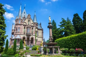 Historisches Schloss mit Türmen und Garten im Vordergrund.