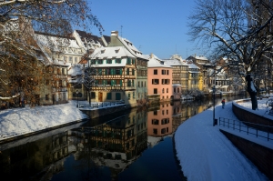 winterliches Straßburg im Elsass, verschneite Häuser, blauer Himmel und ruhiger Fluss