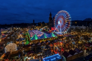 Blick auf bunten Weihnachtsmarkt mit Riesenrad bei Nacht in Maastricht.