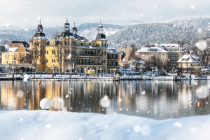 Verschneite Stadt am See mit gelbem Gebäude im Hintergrund.