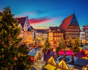 Weihnachtsmarkt mit Lichtern und Fachwerkhäusern bei Sonnenuntergang.