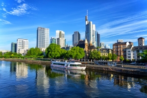 Frankfurter Skyline mit Hochhäusern und dem Main im Vordergrund an einem klaren Tag.
