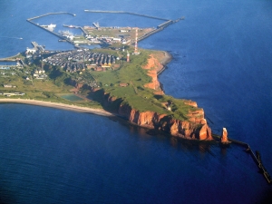 Luftaufnahme einer Insel mit Klippen, Siedlung und Hafenanlagen im Meer.