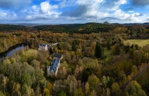 Landschaftsansicht mit Gebäuden und Wald im Herbst.