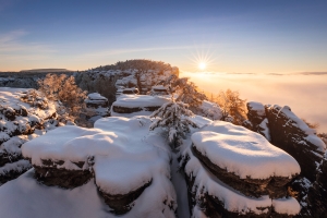 Verschneite Felsenlandschaft bei Sonnenaufgang in einer Bergregion.
