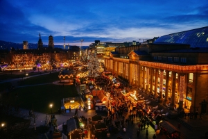 Stuttgarter Weihnachtsmarkt bei Abenddämmerung am Schlossplatz mit beleuchteten Ständen.