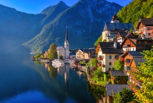 Malerdorf am See mit Kirche und Bergkulisse bei Sonnenuntergang.