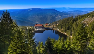 Hütte an einem Bergsee inmitten bewaldeter Berge.