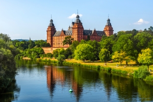 Schloss Johannisburg in Aschaffenburg, Bayern, am Fluss Main, umgeben von grüner Landschaft.
