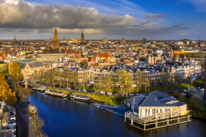Luftaufnahme einer Stadt mit Kanal und historischen Gebäuden bei bewölktem Himmel.