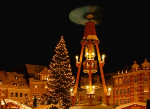 Weihnachtsmarkt: beleuchteter Baum und Pyramide im Dunkeln.