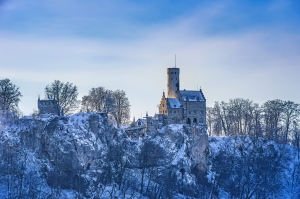 Schloss auf schneebedecktem Hügel im Winter bei blauem Himmel.
