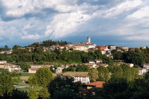 Panoramablick auf eine italienische Stadt mit Hügeln und weitem Himmel im Hintergrund.