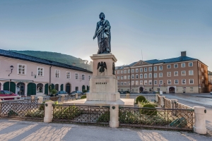 Statue von Mozart auf einem Platz in einer historischen Stadtumgebung.